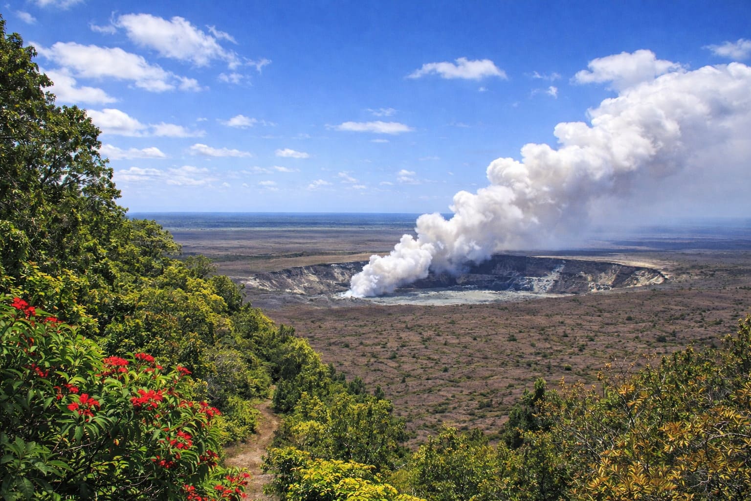 A broad volcanic crater with a white plume on Hawaii Island