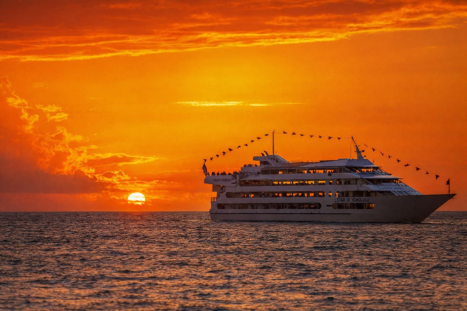 A dinner cruise boat on the ocean at sunset