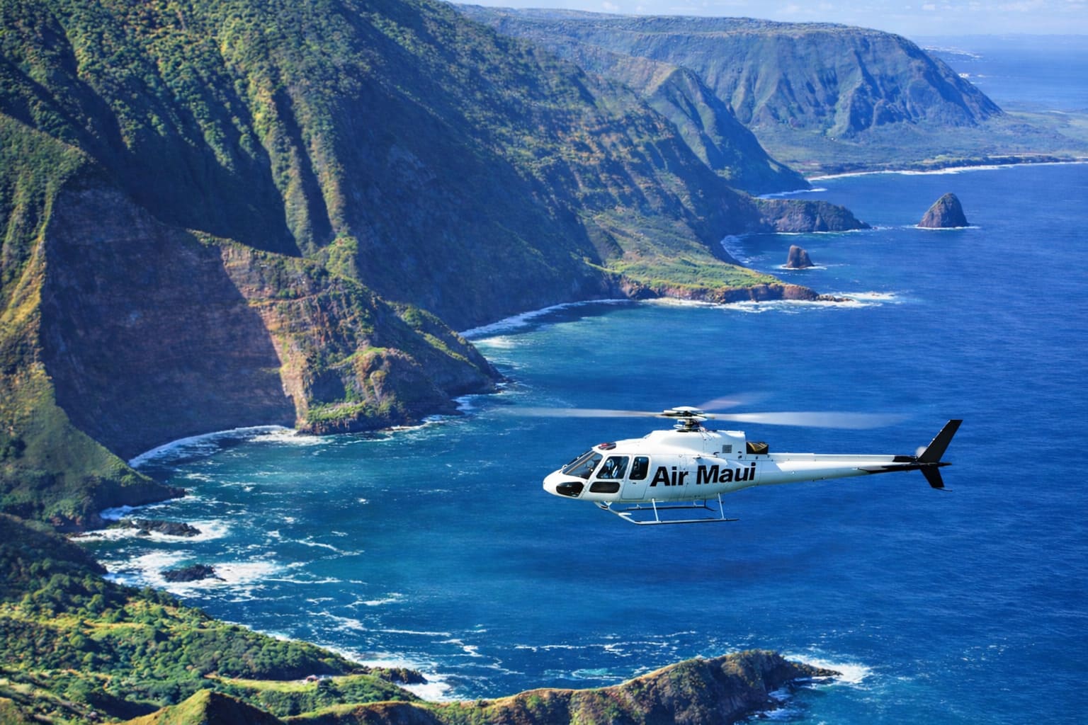 A helicopter flying beside green coastal cliffs